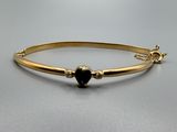 un bracelet rigide en or orné d'un cœur noir
