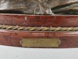 bronze statue of a man with a hat on his head on a wooden base