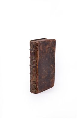 an old book with a brown cover sitting on top of a white surface