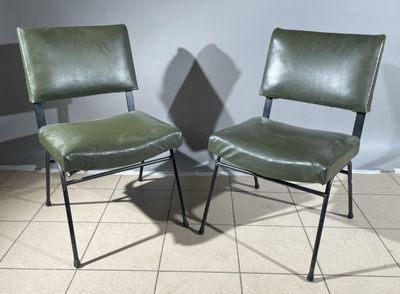 pair of green leather chairs sitting on a tiled floor in front of a wall
