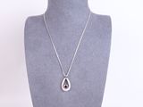 a silver necklace with a tear shaped pendant on a mannequin