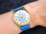 une personne portant au poignet une montre avec un bracelet bleu