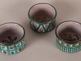 three green and white cups with designs on them sitting on a table