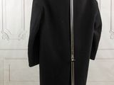 a black coat on a stand in front of a white wall