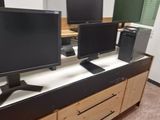 three computer monitors on top of a desk in a room