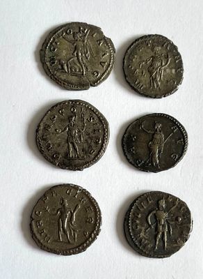six ancient roman coins are shown in a row on a white surface