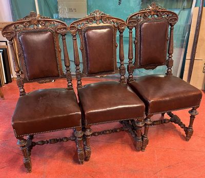 trois fauteuils en cuir marron placés les uns à côté des autres sur un tapis rouge