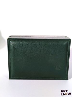 un portefeuille vert posé sur une surface blanche à côté d'une lampe
