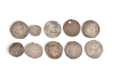 Plusieurs pièces anciennes sont disposées en rangée sur une surface blanche