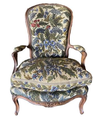 an old chair with a floral upholstered back and arms