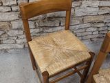 two wooden chairs sitting next to a brick wall