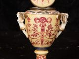 a yellow and red vase with a lid on a black background