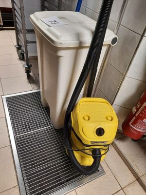 un aspirateur jaune posé par terre à côté d'une poubelle