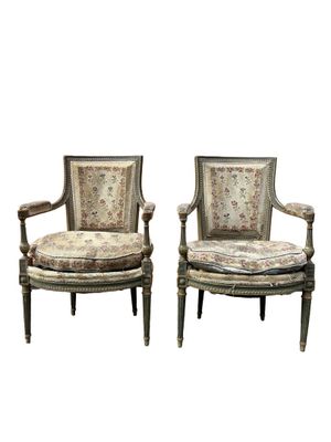 a pair of antique chairs with floral upholstered cushions