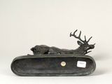 a bronze sculpture of a deer laying down on top of a suitcase