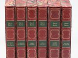quatre livres rouges à la couverture verte sont posés sur une surface blanche