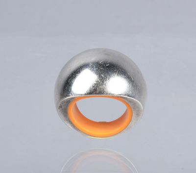 a silver and orange ring on a reflective surface