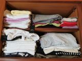 de nombreux vêtements pliés dans un tiroir posé sur une étagère en bois