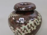 a brown and white vase sitting on a white surface