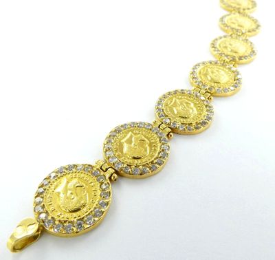 un gros plan d'un bracelet composé de pièces d'or posé sur une surface blanche
