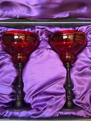 une paire de verres à vin rouge dans une boîte violette, posée sur un tissu violet