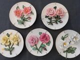 four white plates with pink and yellow flowers on them on a table
