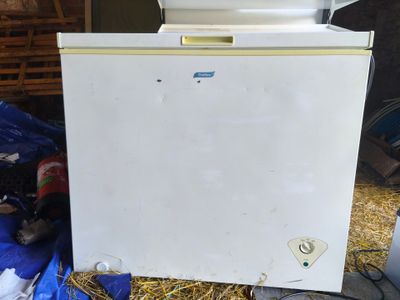 a white freezer sitting on a pile of hay