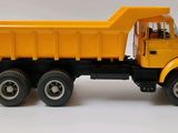 a yellow toy truck that is sitting on a white surface