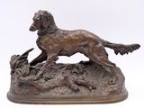 bronze statue of a dog and a bird on a rock