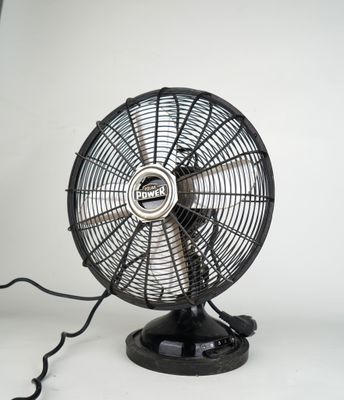 un ventilateur noir posé sur une table blanche