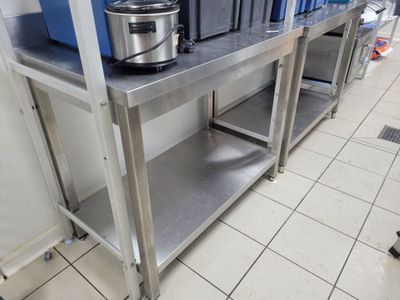 une table en acier inoxydable sur laquelle est posée une mijoteuse