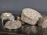 a silver box sitting on top of a table next to other silver objects