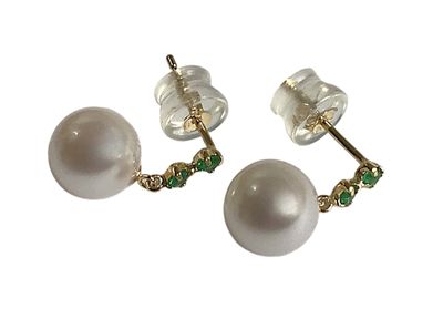 une paire de boucles d'oreilles en perles et émeraudes sur fond blanc