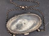 an old silver purse with a chain around it on a table