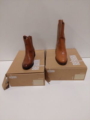 une paire de bottines en cuir marron posées sur une boîte en carton