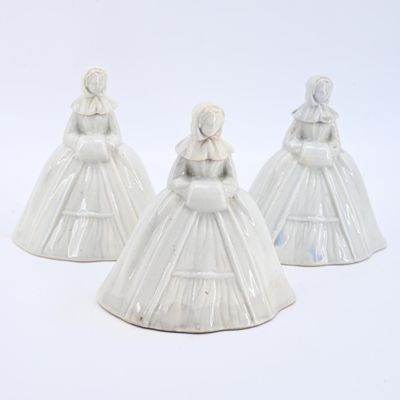 trois figurines en céramique blanche représentant des femmes en robe