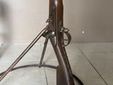 un fusil en bois posé par terre à côté d'une lampe