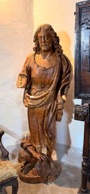 une statue de Jésus debout à côté d'une chaise et d'un miroir