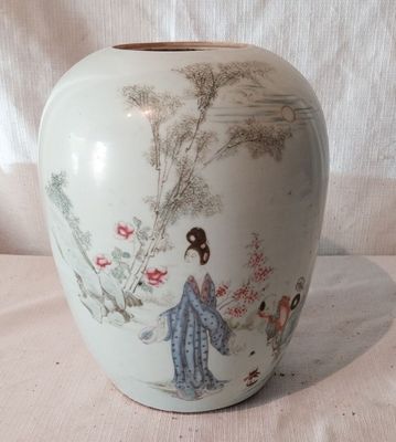 un vase blanc avec un tableau sur une table