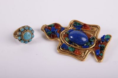 a close up of a broochle and a ring on a white surface
