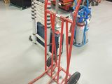 a red hand truck with a stack of ladders on it