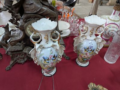 de nombreux vases posés sur une table, avec une statue en arrière-plan