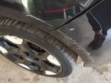 a person standing next to a car that has a tire on it