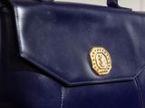 a blue purse with a gold emblem on it