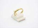 une image représentant une bague en or posée sur un bloc blanc