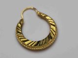 gros plan d'une paire de boucles d'oreilles en or sur une surface blanche