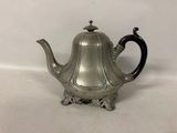 an antique silver teapot with a black handle on a white surface