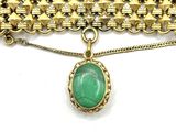 a close up of a necklace with a green stone on it