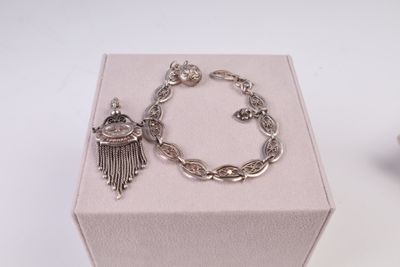 un bracelet en argent orné d'un pompon, posé à côté d'une boîte