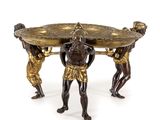 une image représentant une table en bronze sur laquelle trois hommes tiennent un plateau